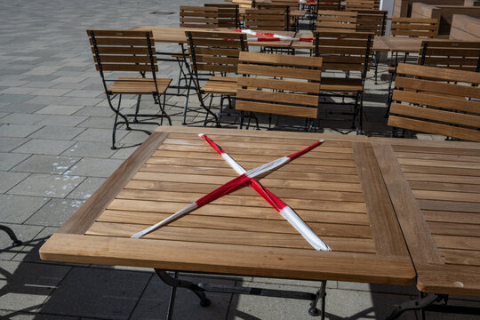 Locked table with red and white flutter band in a street cafe during the coronavirus crisis, keeping the prescribed social distance to reduce the risk of infection
