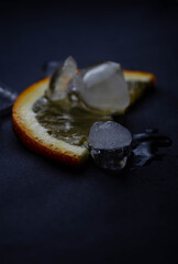 glass of freshly squeezed orange juice with ice on black background