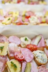 Lots of baguette canapes with cheese and sausage, tomatoes and gherkins on a casual party buffet, copy space