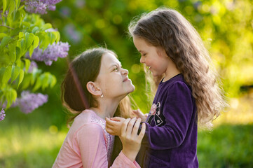 Two sisters play together outside the house in nature.