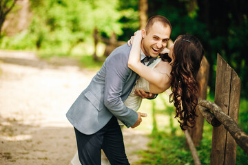 Crazy husband hugs his wife bending her down. Walking the newlywed