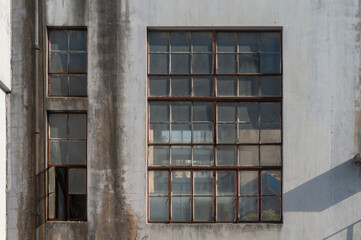 The glass window of the abandoned factory or warehouse in the sunny day. Retro style scene of the industrial factory or warehouse in rural area. Urban scene of Shanghai. Old building of the plant