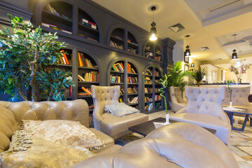 Interior of a hotel lounge with leather furniture and bookshelf