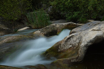 Naklejka na ściany i meble water flows between the rocks. long exposure river flowing between rocks.