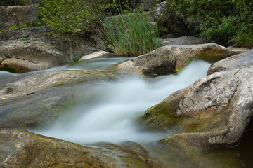 Naklejka na ściany i meble water flows between the rocks. long exposure river flowing between rocks.