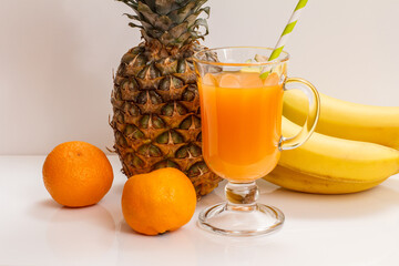 Fresh tropical fruits and glass of juice on white background.