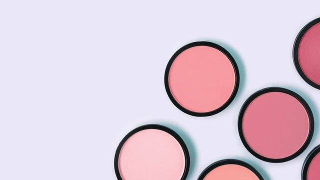 Pink blush and compact powder on trendy pastel blue background. Place text. Top view. Beauty colors, eyeshadow. Makeup. Cosmetic products. Tonal foundation. Flat lay. Copy space. Stop motion animation