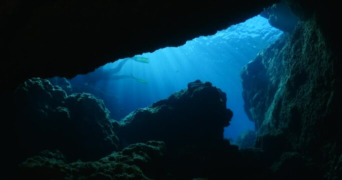 cave diving underwater scuba divers exploring caves ocean scenery sun beams and rays background