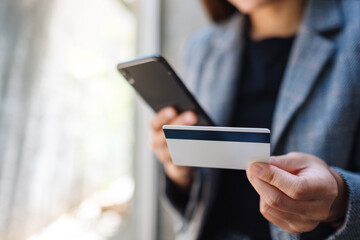 Closeup image of a woman using credit card for purchasing and shopping online on mobile phone