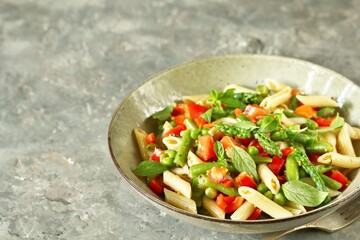 salad in a bowl of pasta, asparagus, bean pods, tomatoes, green peas, basil.