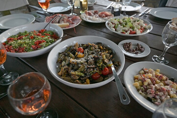 large table prepared with mediterranean vegetables, salads  and antipasti for a rustic dinner party