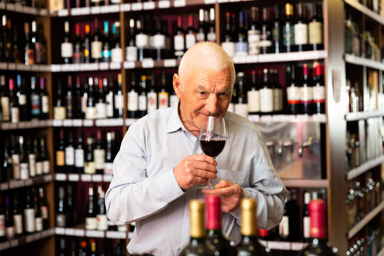 Elderly man smells the quality of red wine