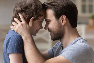 Loving young father and preschooler son look in eyes touch foreheads enjoy close tender family moment together, happy dad and little boy child hug embrace show care and support, bonding concept