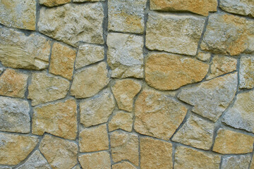 Wall of stone. Stones of various shapes with yellow spots.