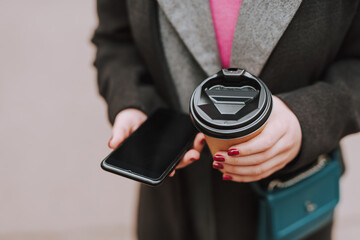 Modern gadget and coffee to go in hands of woman