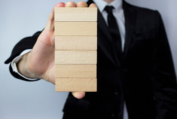 Planning, risk and strategy in business, a businessman holds six wooden blocks in his hand in close-up with a place for your text.