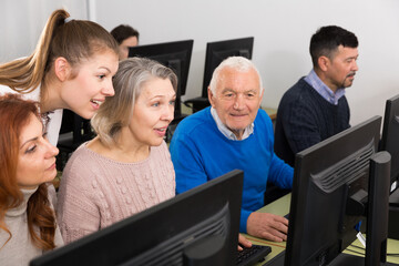 Young and mature  partners grouped around computer monitor