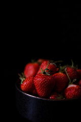 Fresh strawberries on dark moody background. Dark food photography.
