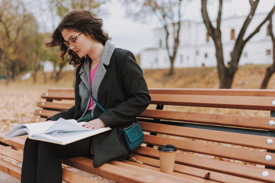 Pretty woman sitting with coffee abd book outdoors