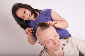 Fototapeta na wymiar Woman doing haircut for man at home while Covid-19 quarantine. Self isolation family lifestyle.