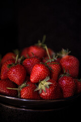 Fresh strawberries on dark moody background. Dark food photography.