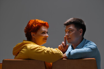 cheerful couple holding hands and sitting on chairs