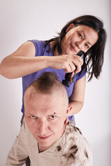 Woman doing haircut for man at home while Covid-19 quarantine. Self isolation family lifestyle.