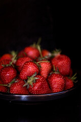 Fresh strawberries on dark moody background. Dark food photography.