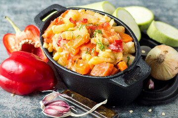 Vegetable stew. Stewed vegetables in a tall cast-iron frying pan on an old table. Vegetarian...