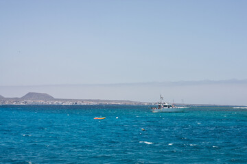 Seascape with white capped waves, a dive boat and blue sky looking towards Corralejo Fuertaventura from the sea. Space left for copy text