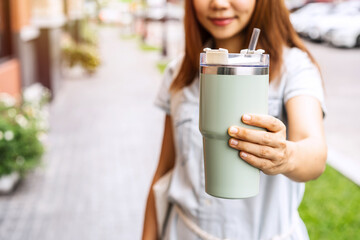 Young asian woman holding a reusable tumbler glass and walking in the city, Zero waste concept