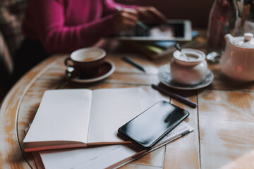 Notebooks and phone on a wooden table in a cafe