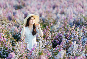 Beautiful Asian woman wear white dress and white hat walking in margaret flowers garden.