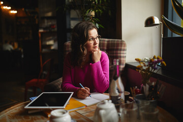 Pretty young woman looking out the window in cafe