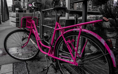 Fototapeta na wymiar black and white photography of a dutch style pink bicycle locked to a railing at busanbrücke in the hafencity hamburg on a rainy day