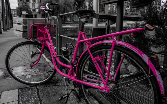 black and white photography of a dutch style pink bicycle locked to a railing at busanbrücke in the hafencity hamburg on a rainy day