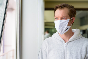 Face of young man with mask thinking and looking out the window ready for gym