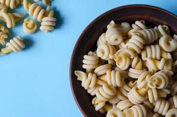 Serving Uncooked insalatonde pasta in a bowl on a light blue background.