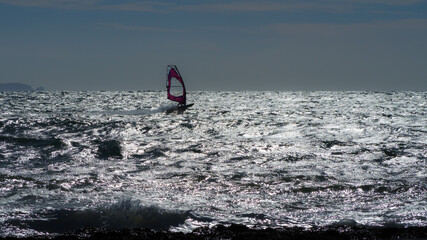 a windsurfer is racing over the rough mediterranean sea