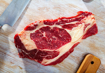 Raw beef entrecote steak ready for cooking on wooden surface