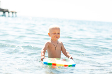 Fototapeta na wymiar Happy baby boy playing in the waves at the seaside