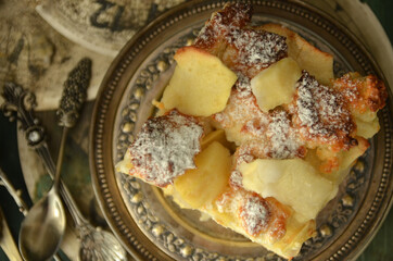 A square piece of apple pie on a rustic plate
