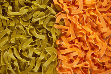 Green and orange dry uncooked pasta background