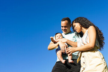 Happy family walking. mother and father looking the baby - isolated over light blue background - Image