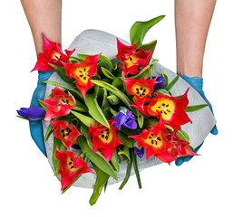 Contactless flower delivery, male courier in medical gloves with a bouquet of red tulips and irises, concept of a flower business during a pandemic, health safety.