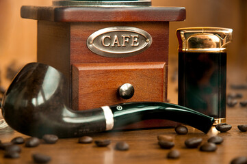 Still life "Pleasure and sins" with smoking pipe, a vintage coffee grinder and coffee beans	