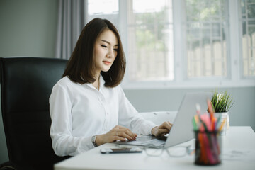 Portrait of smiling pretty young business woman in glasses sitting on workplace