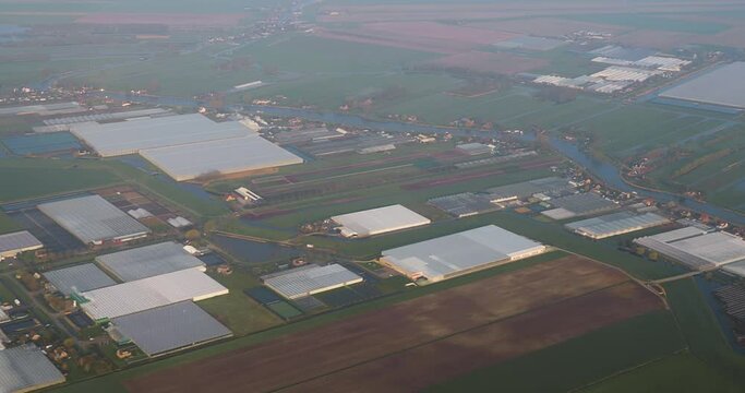 View from plane window during approach, landing in The Netherlands. Fields and greenhouses