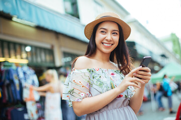 Young beautiful woman smiling happy walking on city streets on a sunny day of summer using smartphone