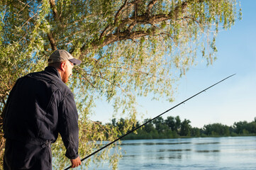 Fisherman with a fishing rod on the river Bank. Fishing at sunset  for spinning. Outdoor recreation